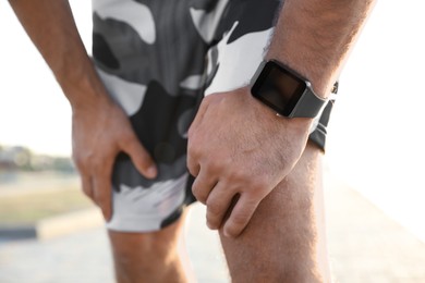 Photo of Man with fitness tracker after training outdoors, closeup