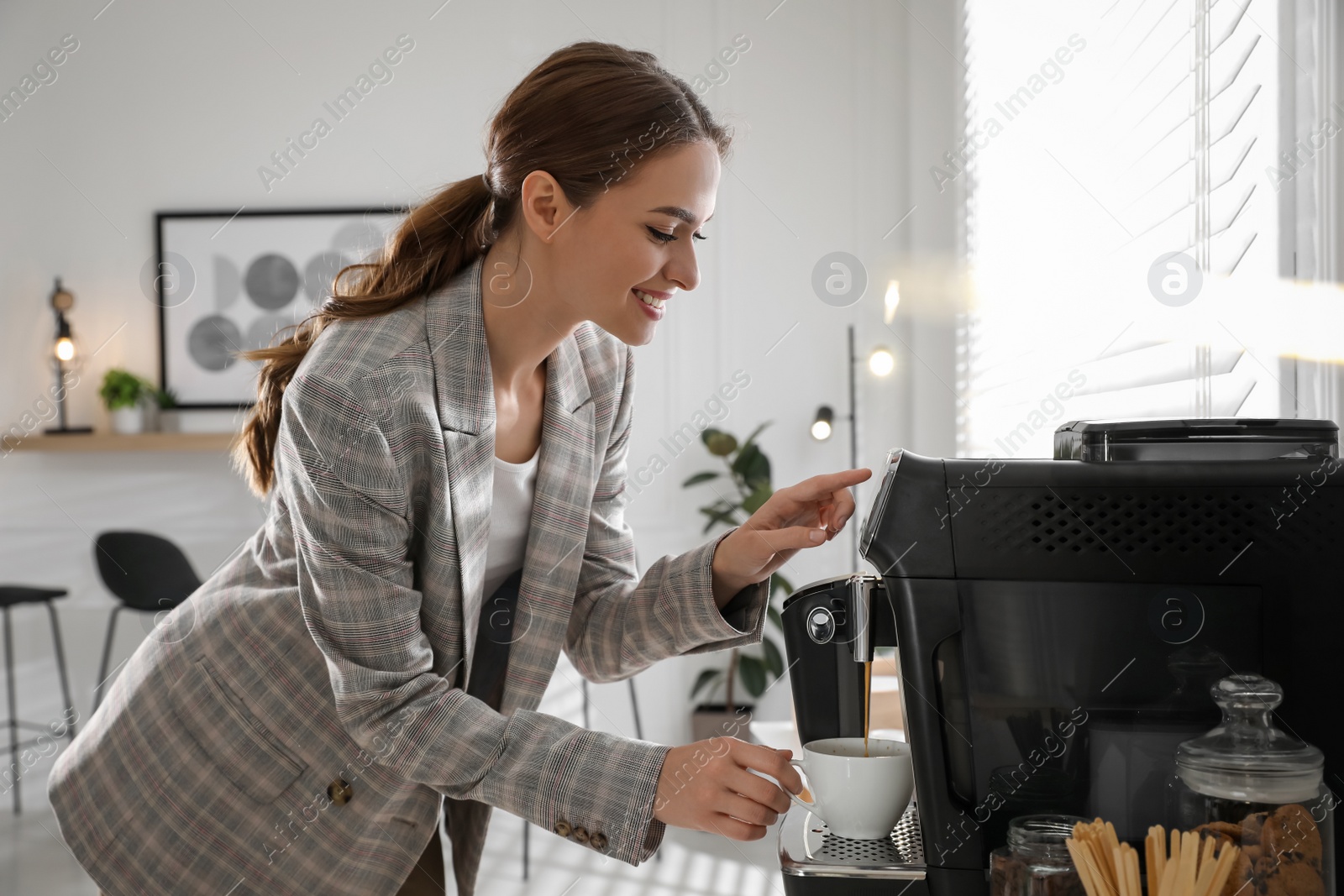 Photo of Young woman preparing fresh aromatic coffee with modern machine in office