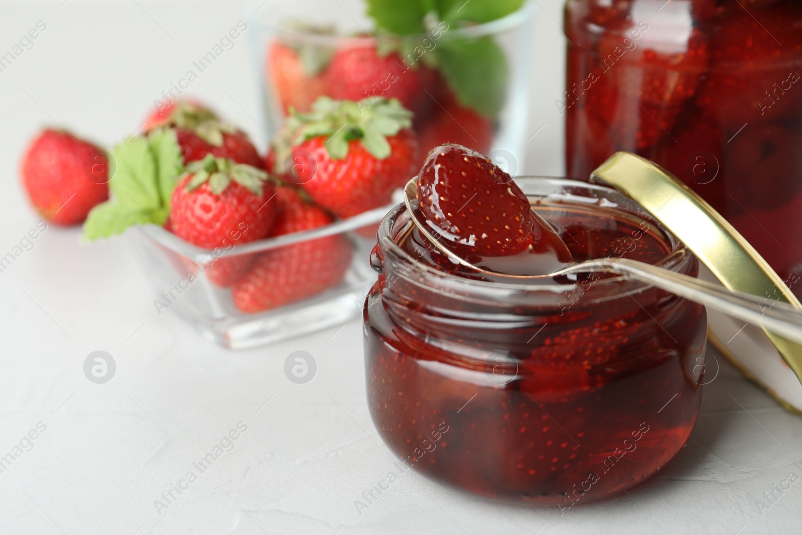 Photo of Delicious pickled strawberry jam and fresh berries on light table. Space for text