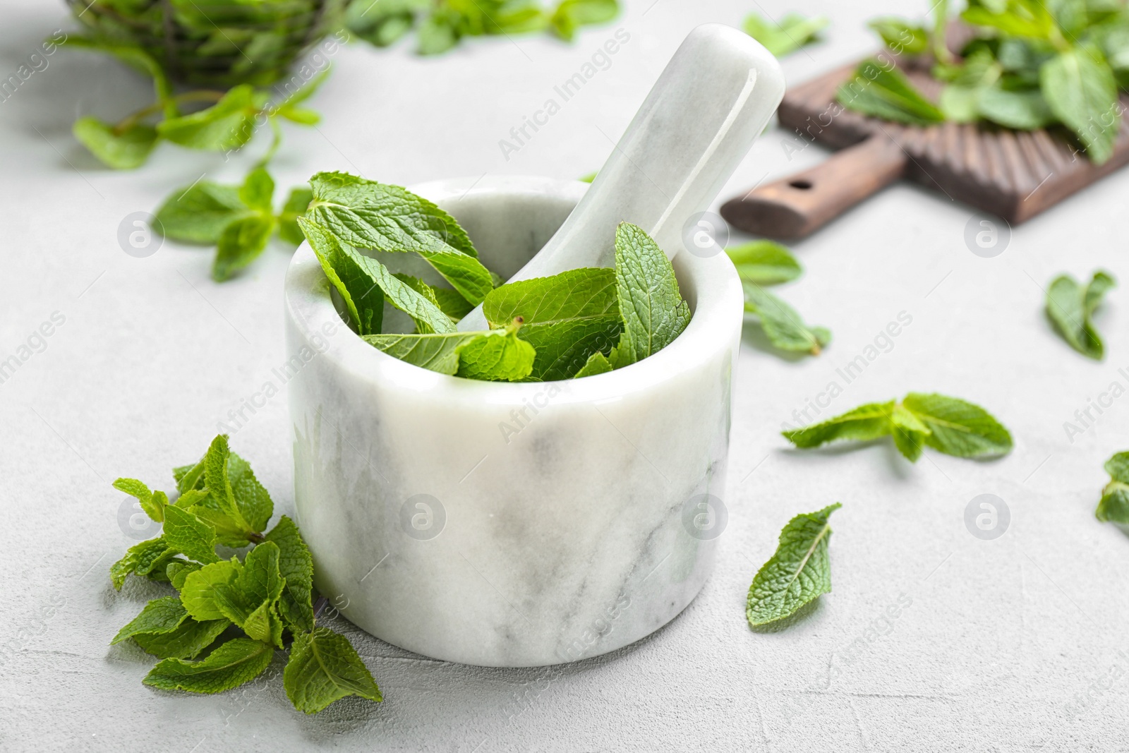 Photo of Marble mortar with pestle and fresh mint leaves on table