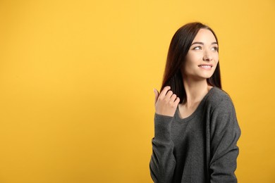 Photo of Portrait of pretty young woman with gorgeous chestnut hair and charming smile on yellow background, space for text