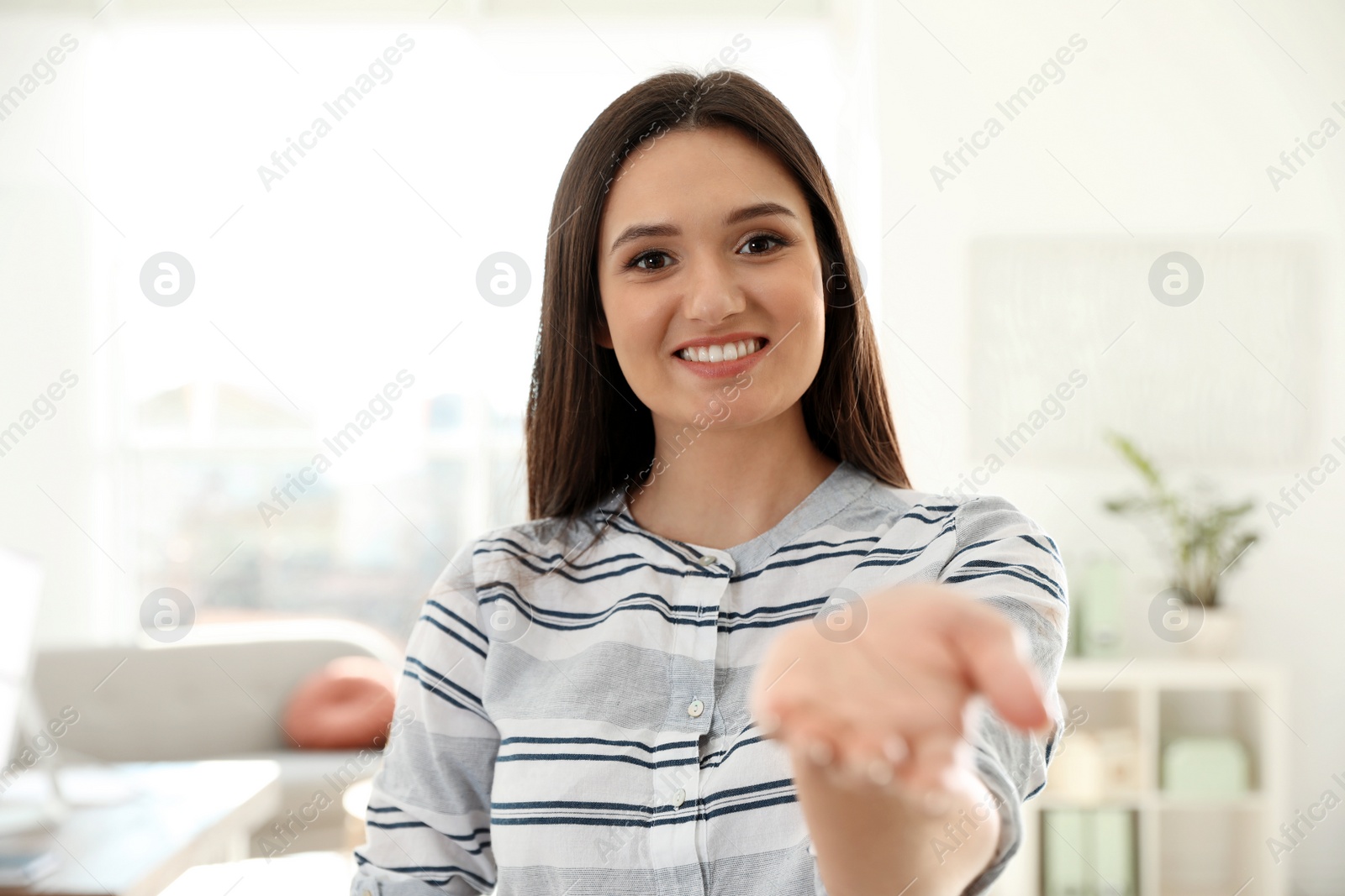 Photo of Young woman looking at camera and using video chat in home office