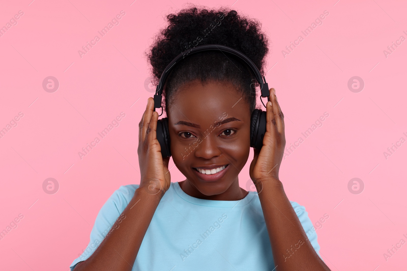 Photo of Young woman in headphones enjoying music on pink background