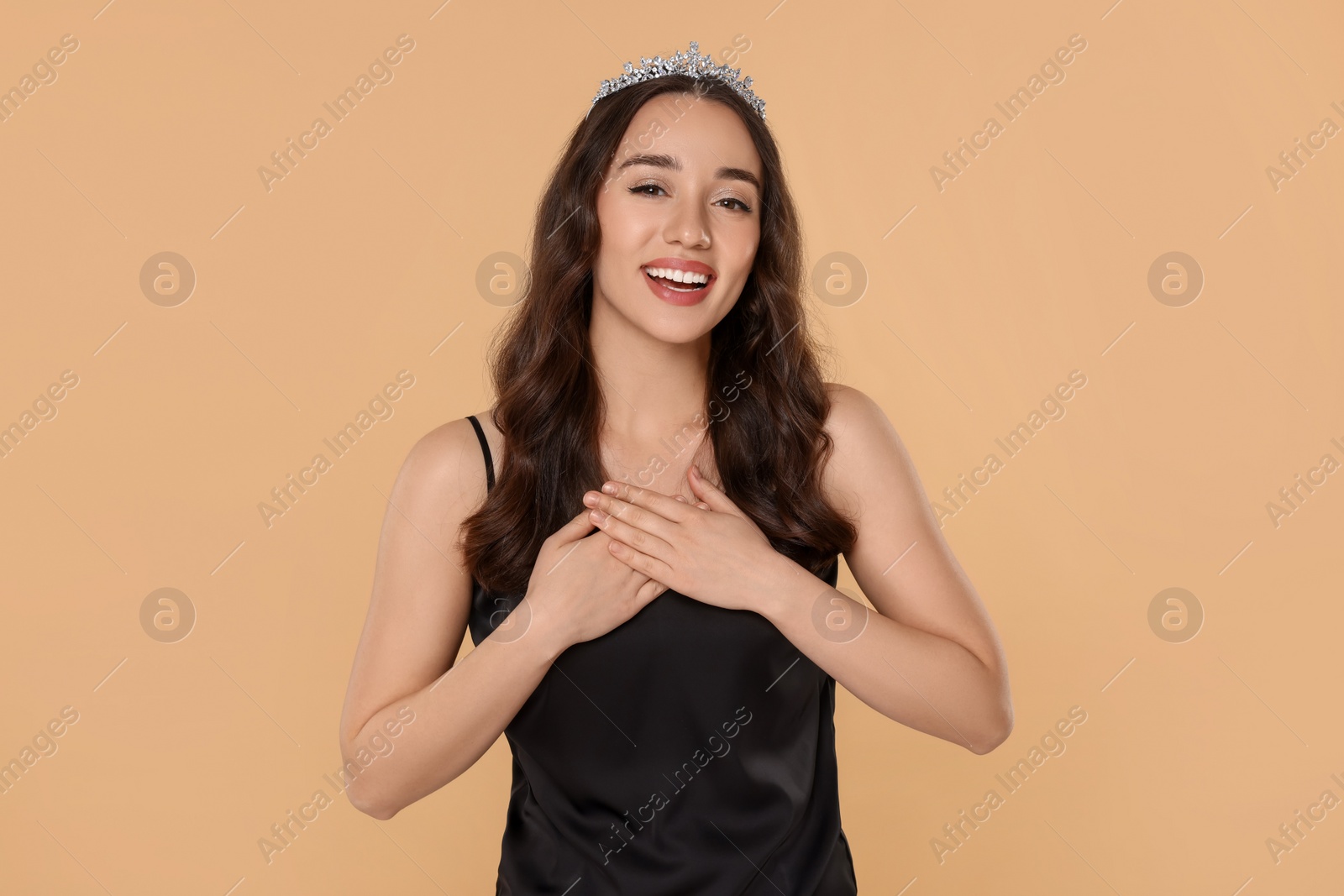 Photo of Beautiful young woman with tiara in stylish dress on beige background