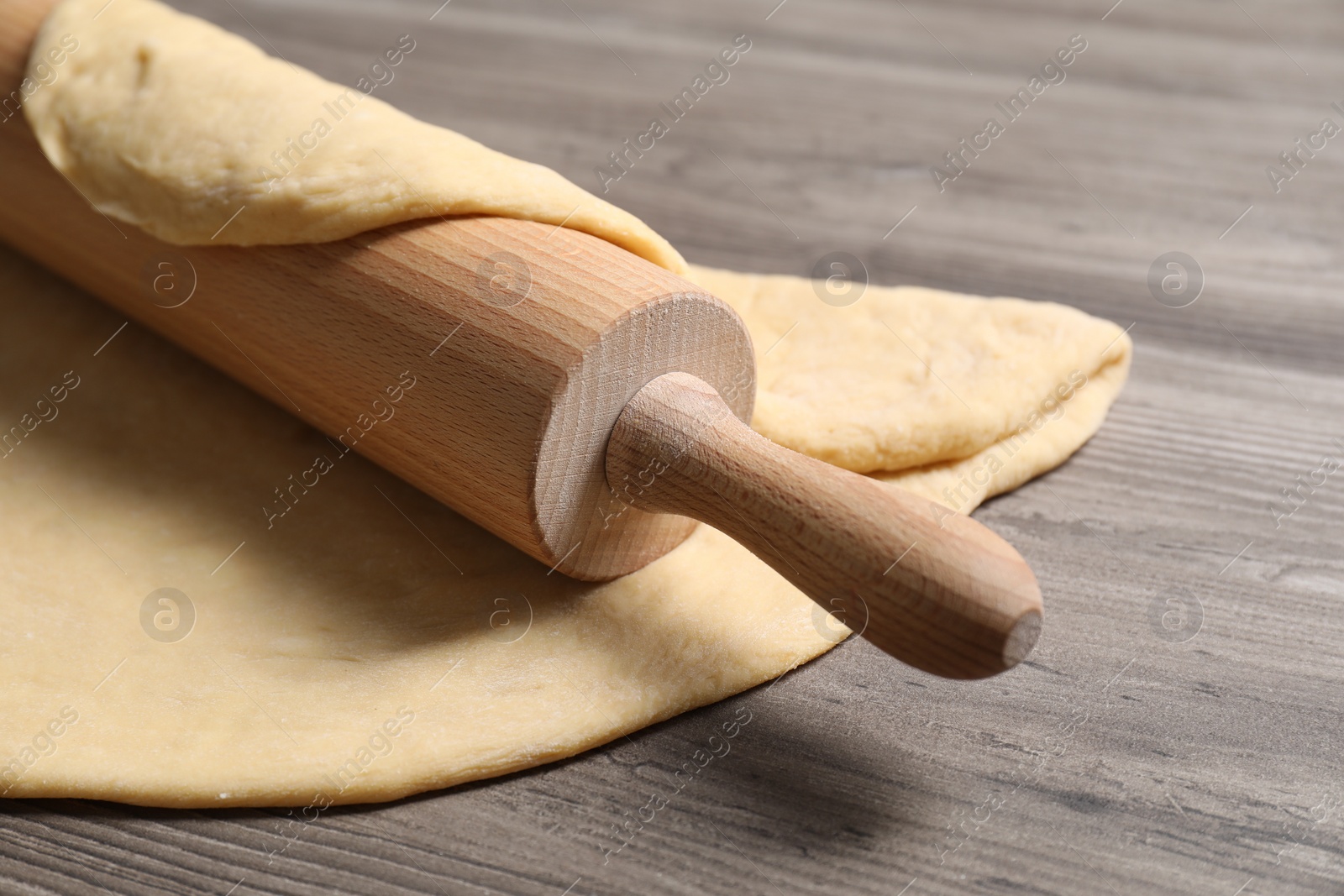 Photo of Raw dough and rolling pin on wooden table, closeup