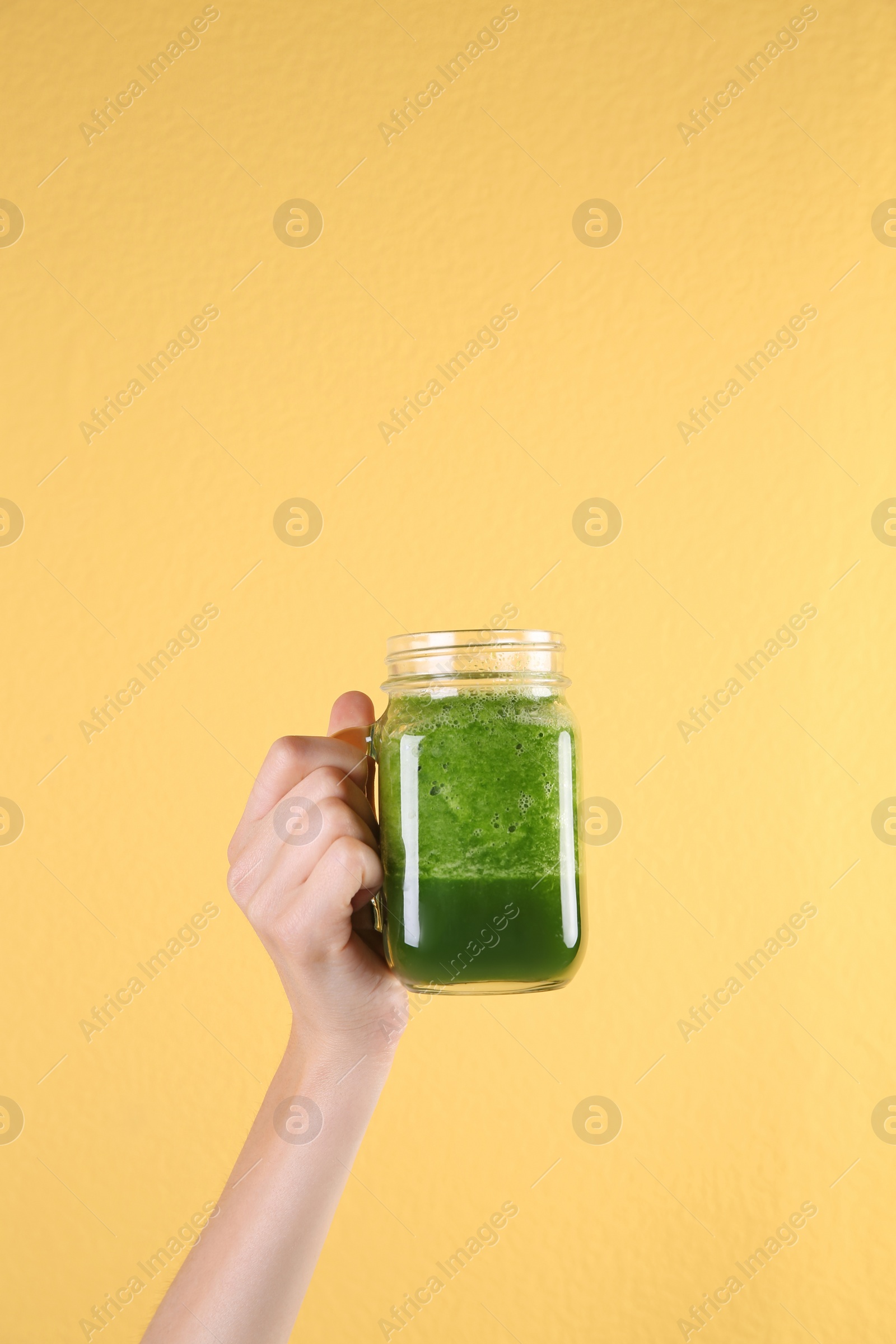 Photo of Young woman holding mason jar of healthy smoothie on color background