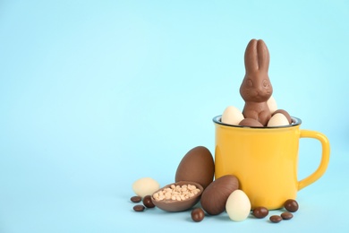 Photo of Chocolate Easter bunny, eggs and candies on light blue background. Space for text