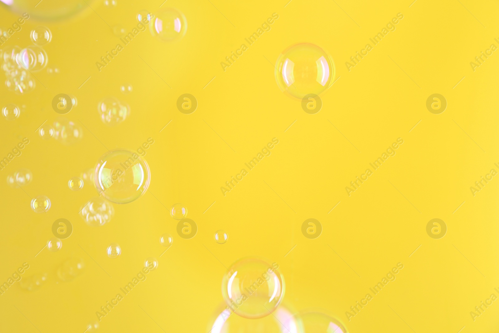 Photo of Beautiful transparent soap bubbles on yellow background, space for text