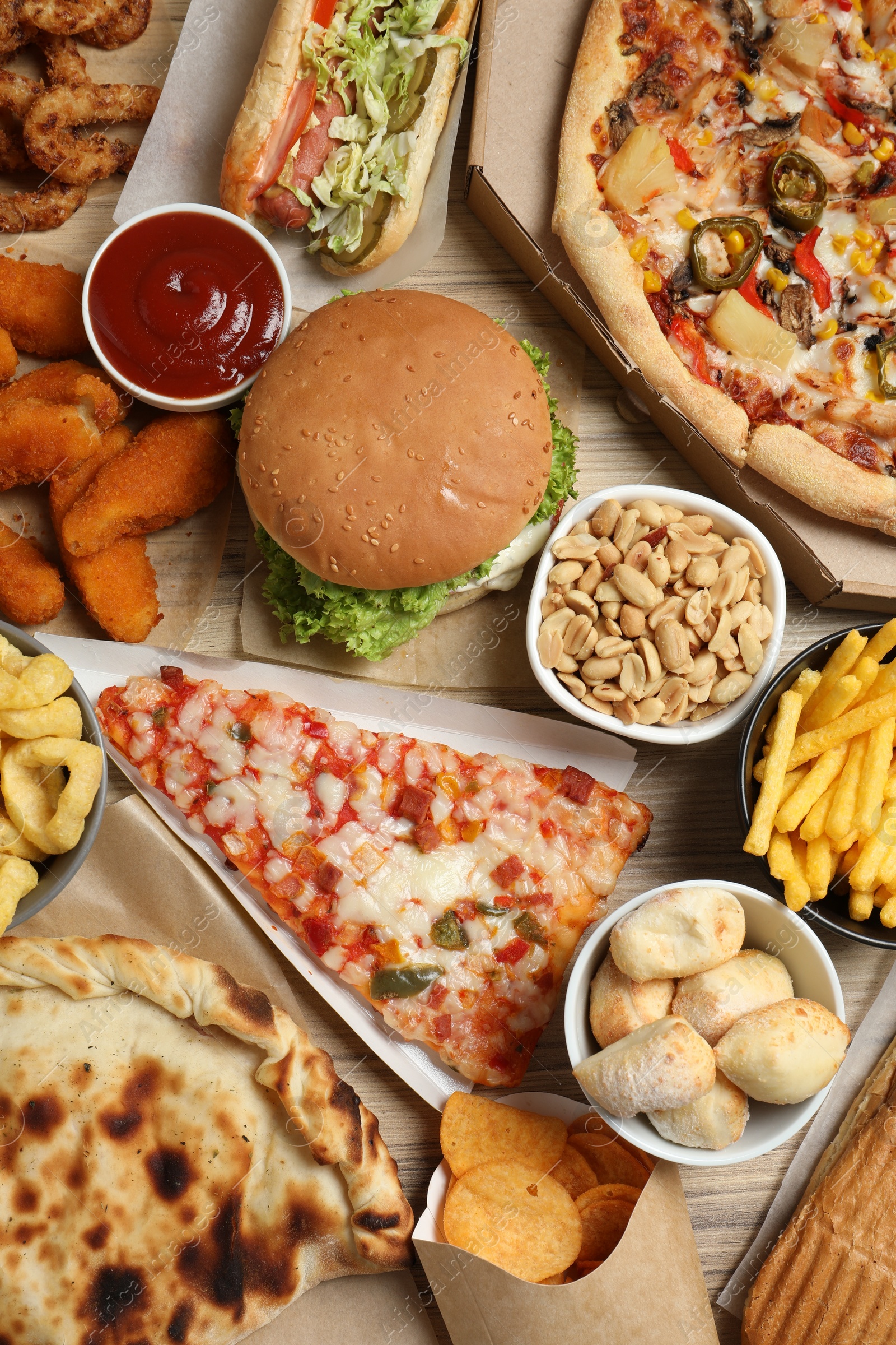 Photo of French fries, pizza and other fast food on wooden table, flat lay