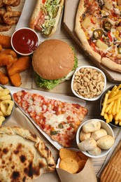 French fries, pizza and other fast food on wooden table, flat lay