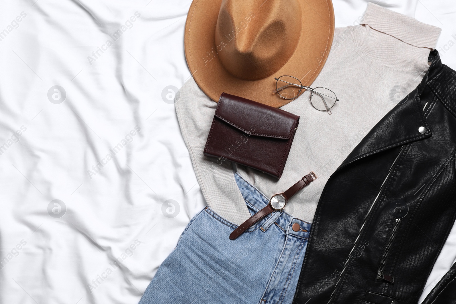 Photo of Flat lay composition with stylish hat and autumn clothes on white fabric, space for text