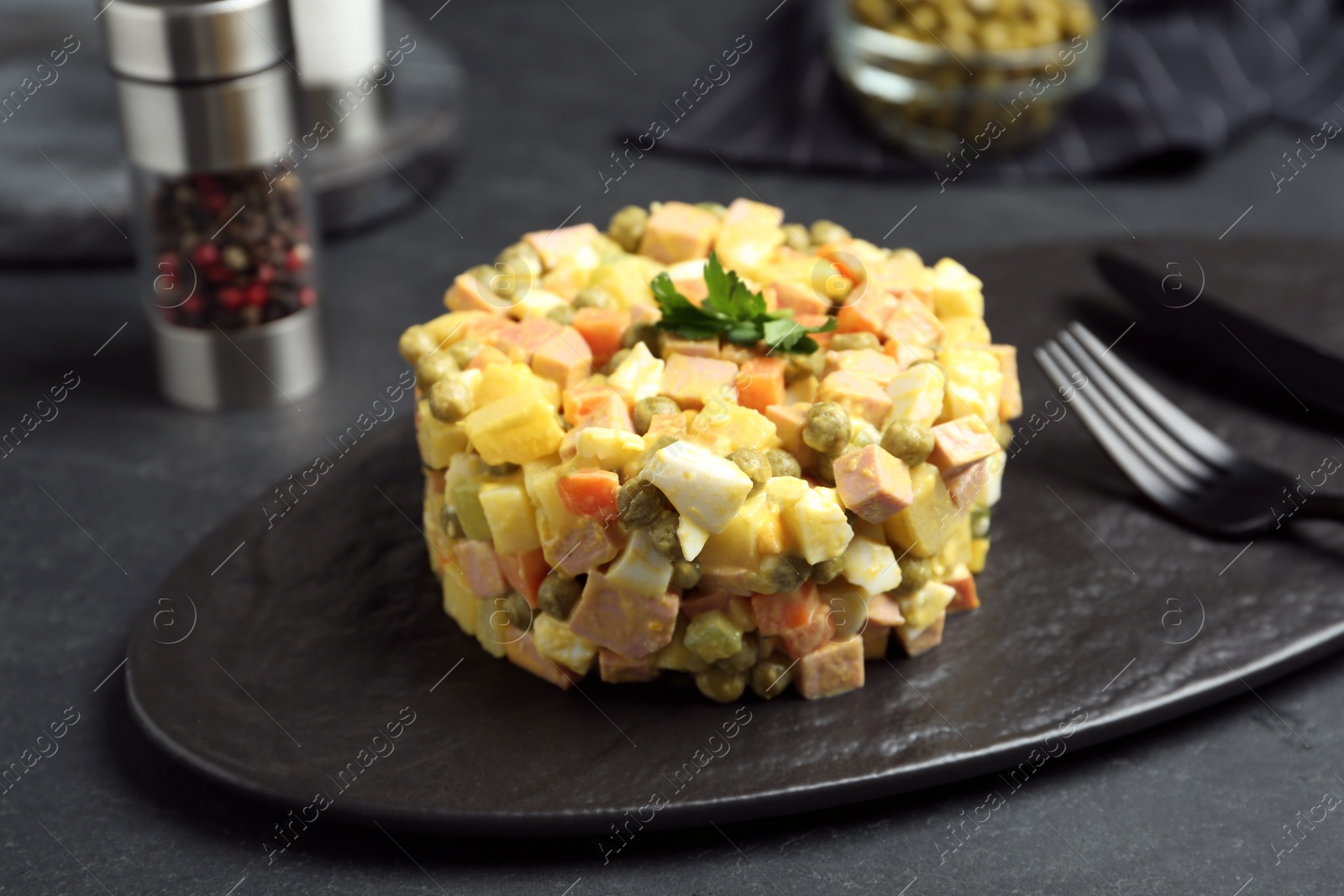 Photo of Delicious russian salad Olivier served on black table
