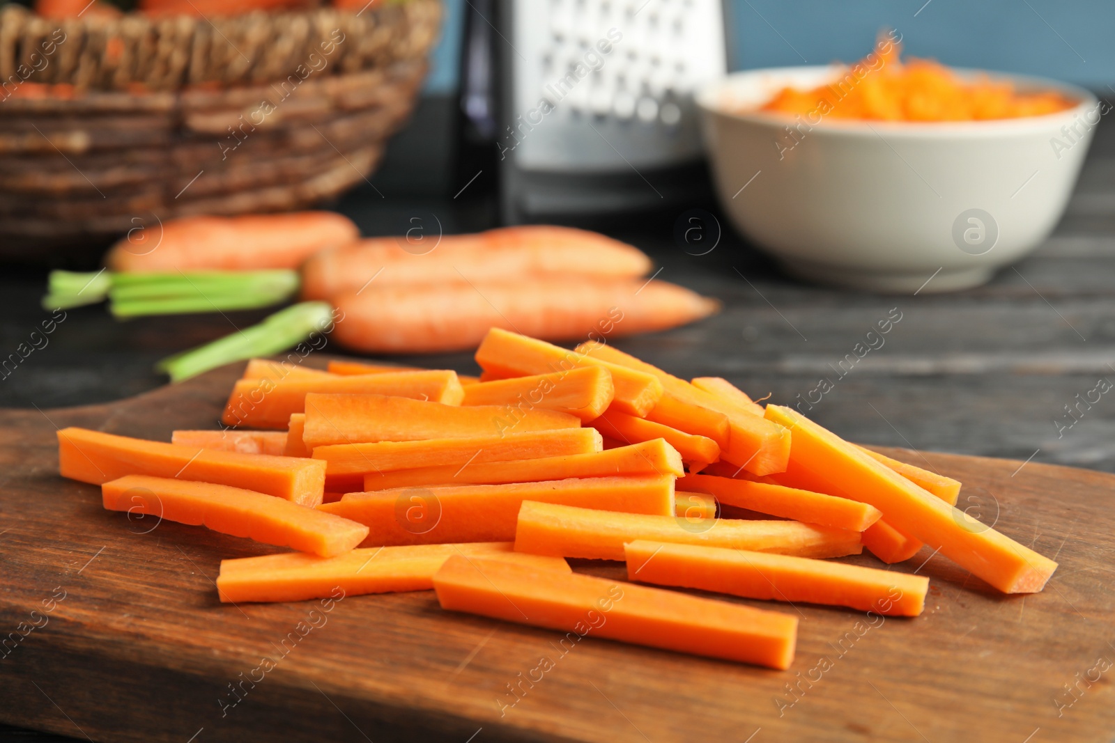 Photo of Wooden board with carrot sticks on table