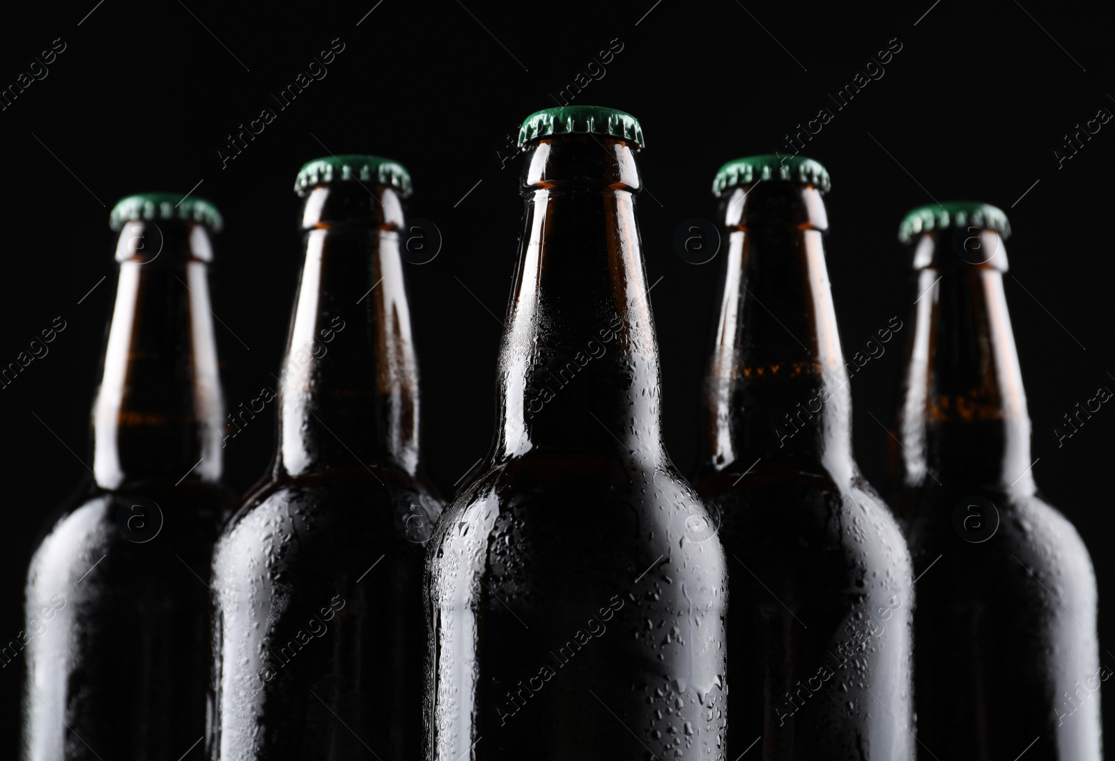 Photo of Many bottles of beer on black background, closeup