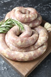 Raw homemade sausage, rosemary and garlic on grey textured table, closeup