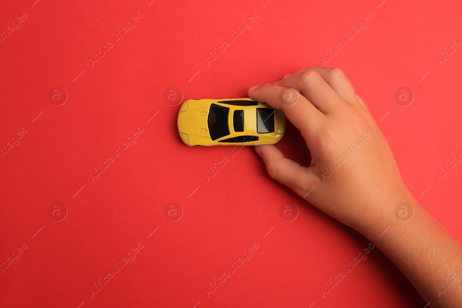 Photo of Child playing with toy car on red background, top view. Space for text