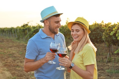 Photo of Young couple holding glasses of wine at  vineyard