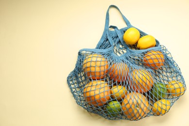 String bag with different fruits on beige background, top view. Space for text