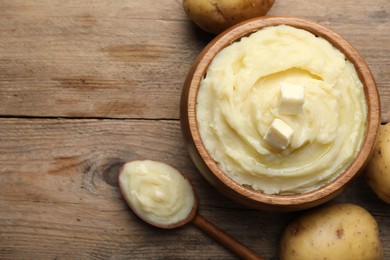 Bowl of delicious mashed potato with butter on wooden table, flat lay. Space for text