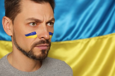 Photo of Man with face paint near Ukrainian flag, closeup. Space for text