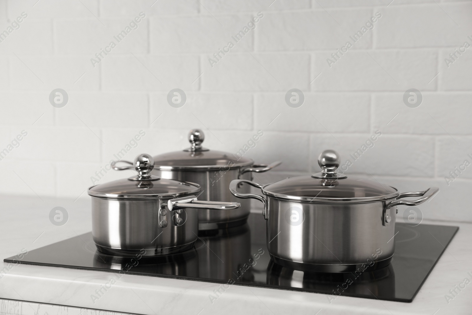 Photo of Set of new clean cookware on cooktop in kitchen