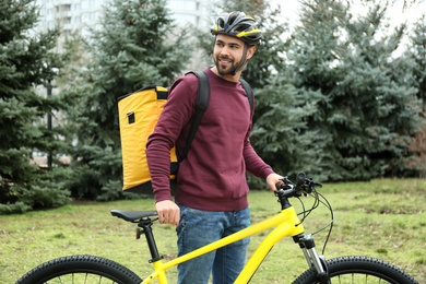 Photo of Courier with thermo bag and bicycle outdoors. Food delivery service