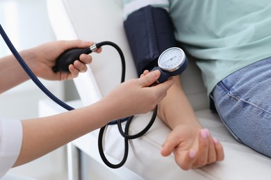 Doctor checking blood pressure of woman in clinic, closeup