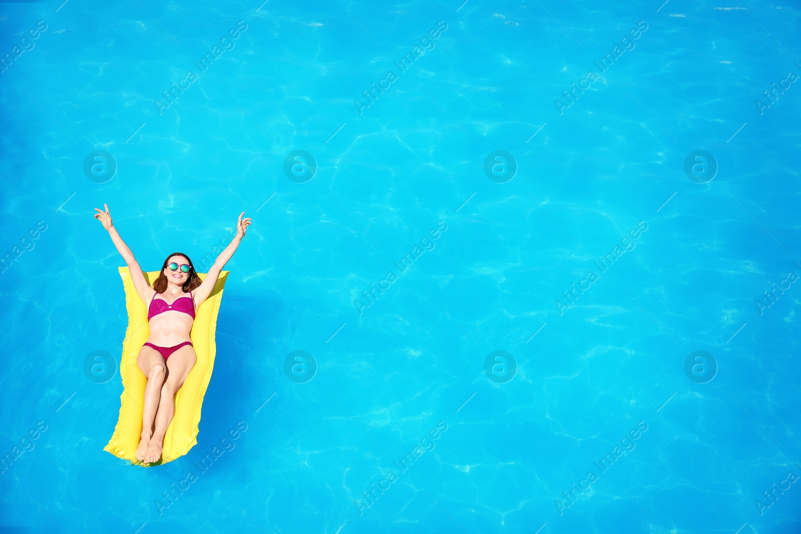 Photo of Young woman on inflatable mattress in swimming pool, above view