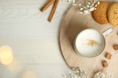 Photo of Cup of hot coffee, cookies, brown sugar and flowers on white wooden table, flat lay. Space for text