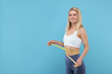 Photo of Slim woman measuring waist with tape on light blue background, space for text. Weight loss