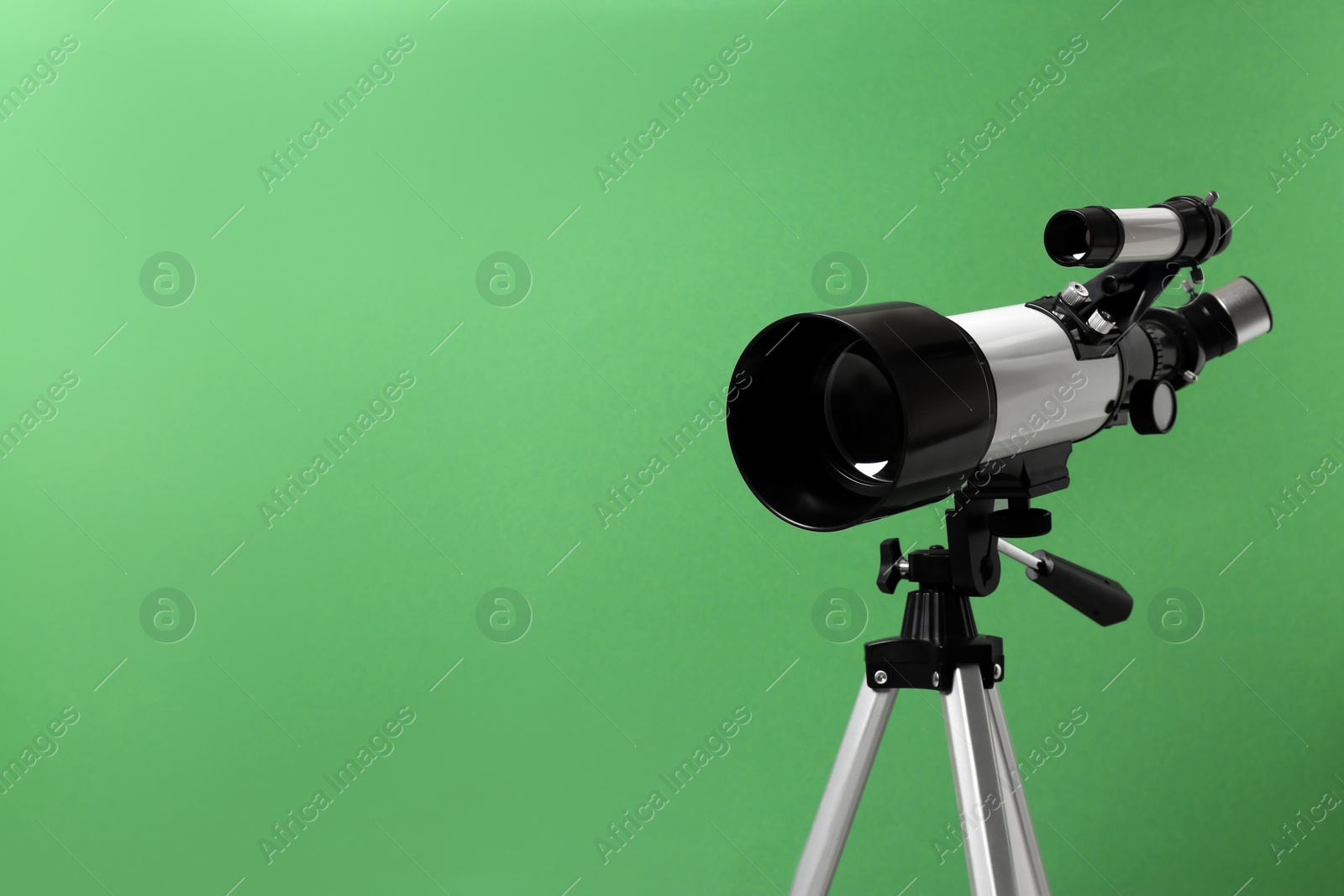 Photo of Tripod with modern telescope on green background, closeup. Space for text