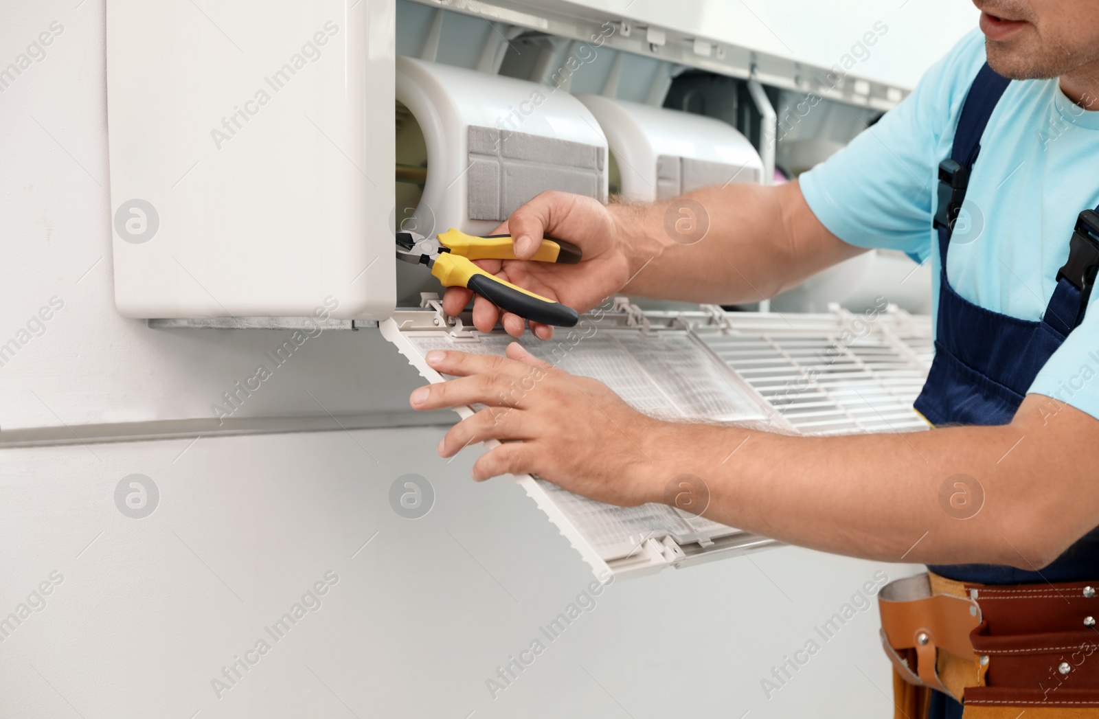 Photo of Male technician repairing modern air conditioner indoors