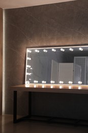 Photo of Modern mirror with light bulbs on wooden table in room