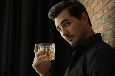 Photo of Young man with glass of whiskey indoors