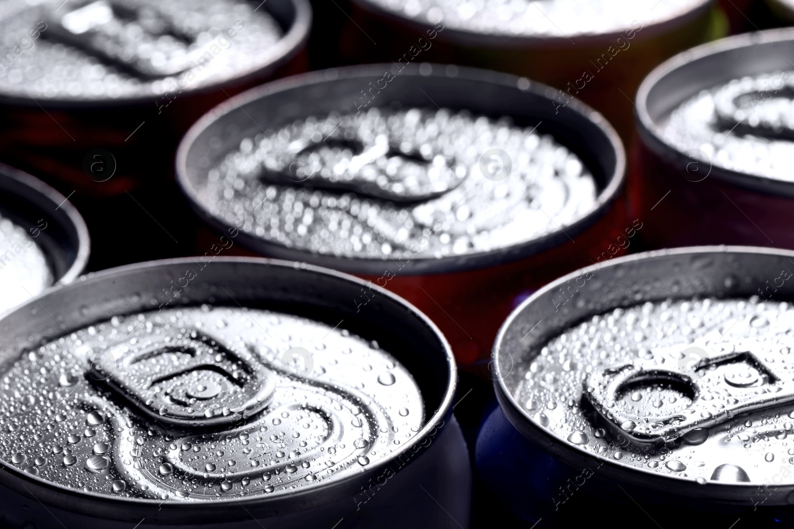 Photo of Aluminum cans of beverage covered with water drops as background, closeup