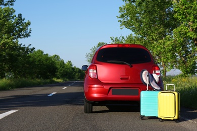 Photo of Color suitcases with hat near family car on highway. Space for text