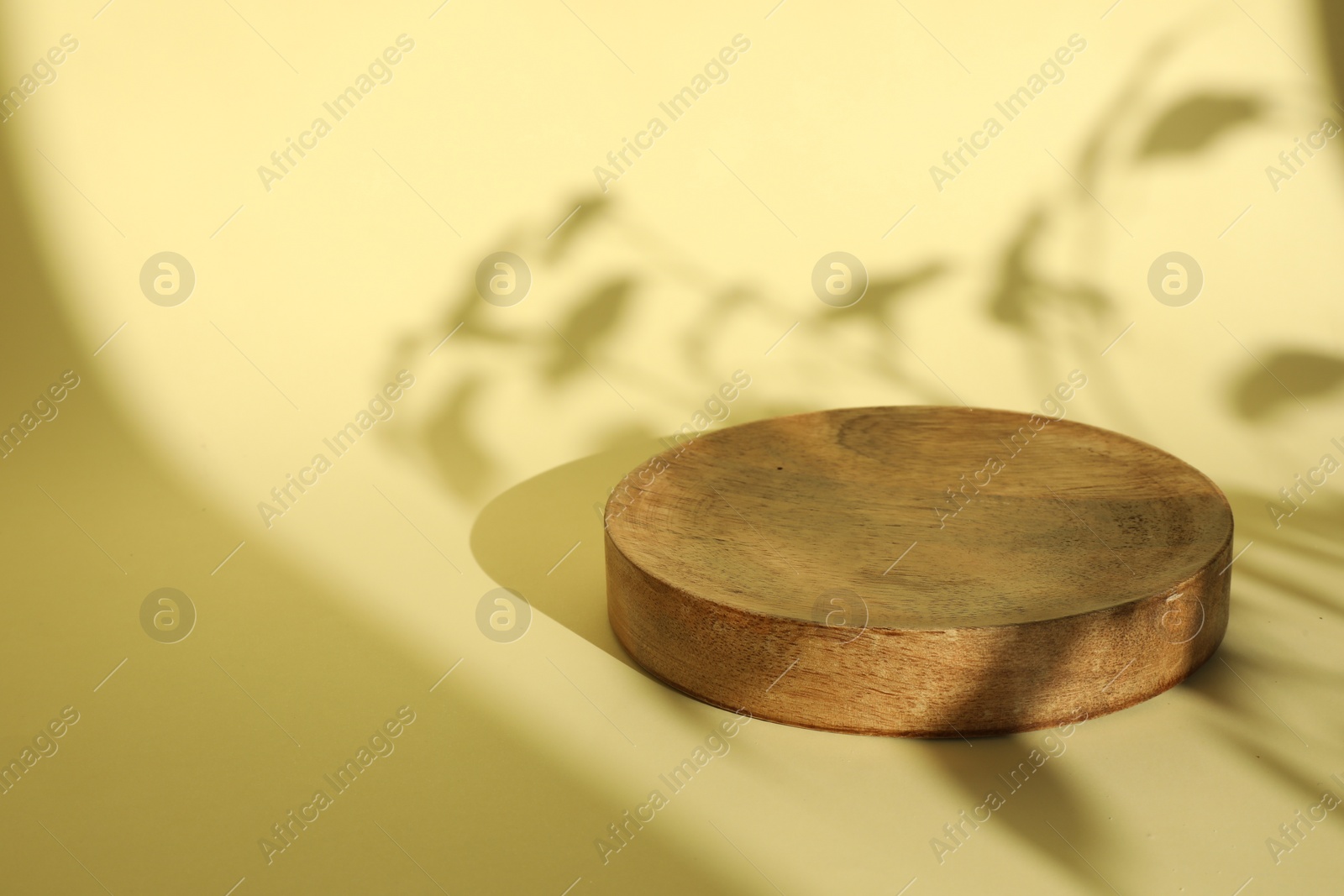 Photo of Presentation of product. Wooden podium on yellow background. Space for text