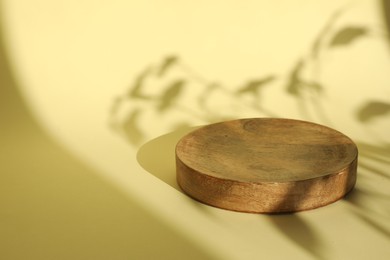 Photo of Presentation of product. Wooden podium on yellow background. Space for text