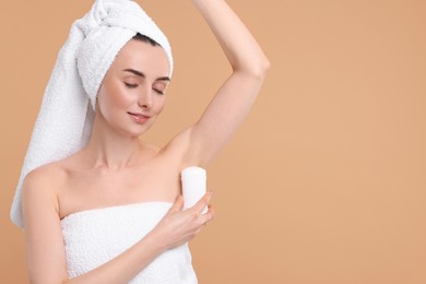 Photo of Beautiful woman applying deodorant on beige background, space for text