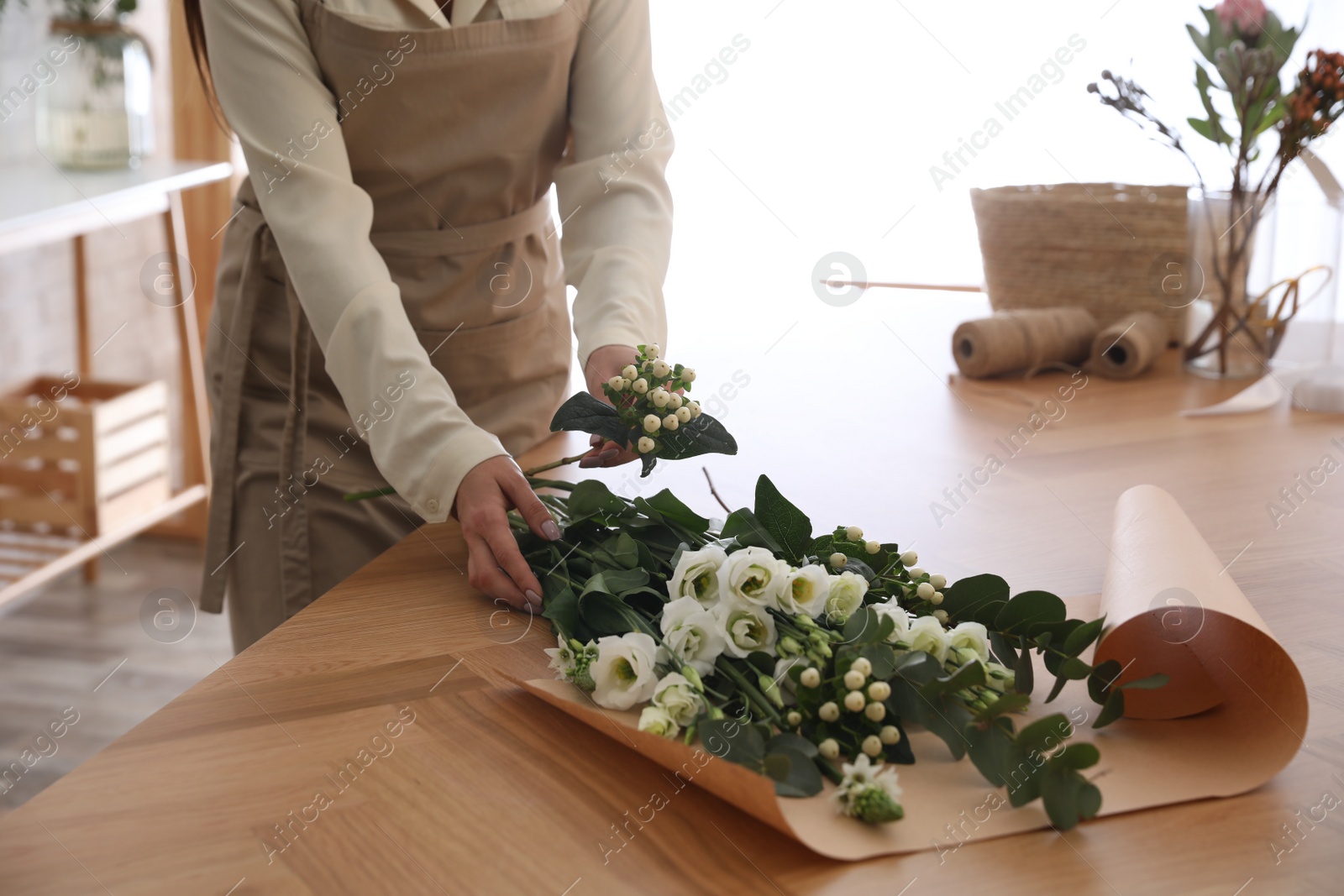 Photo of Florist making beautiful bouquet at table in workshop, closeup