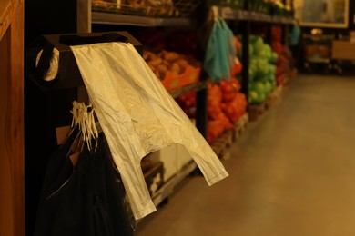 Plastic bags near rack with fruits in supermarket, space for text
