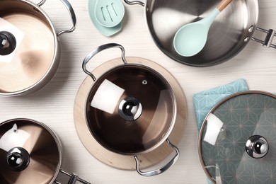 New cookware set and kitchen utensils on white wooden table, flat lay