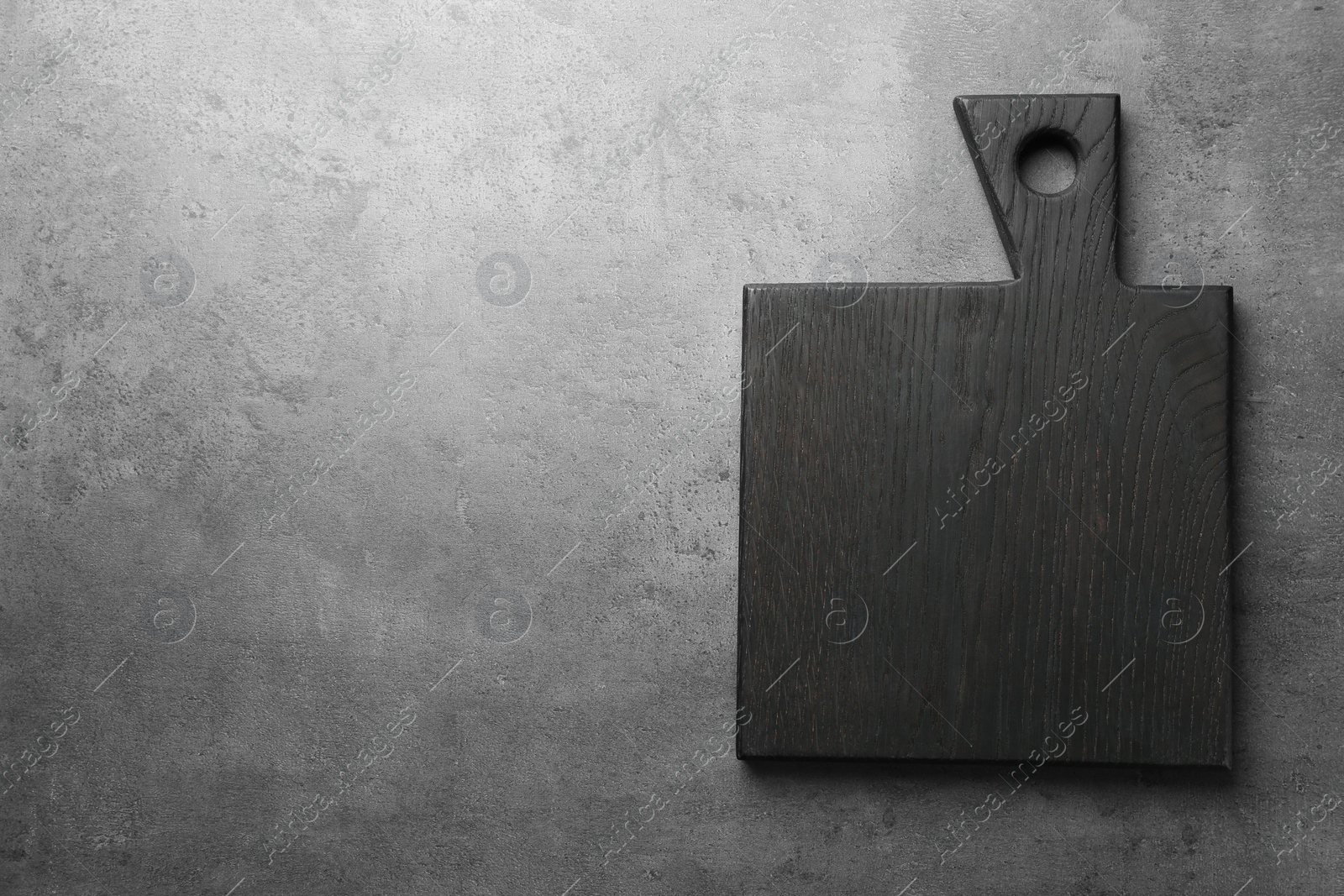 Photo of Black cutting board on grey table, top view. Space for text