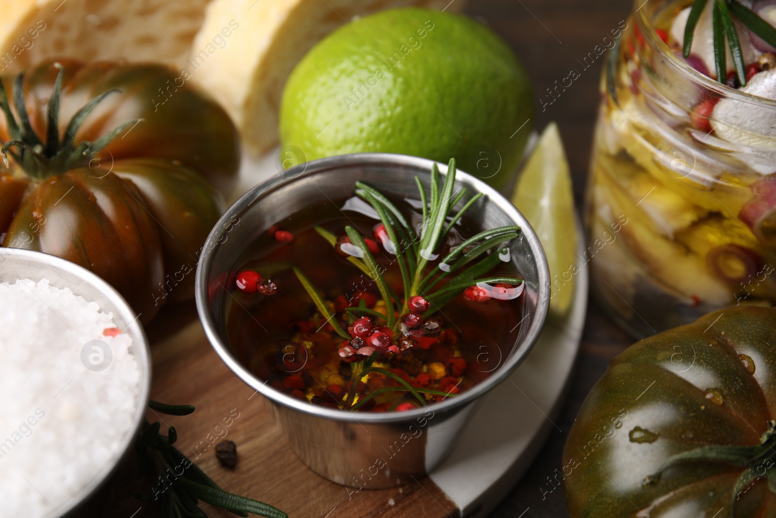 Photo of Tasty fish marinade with rosemary in bowl and products on table, closeup