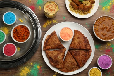 Photo of Traditional Indian food and color powders on wooden table, flat lay. Holi festival celebration