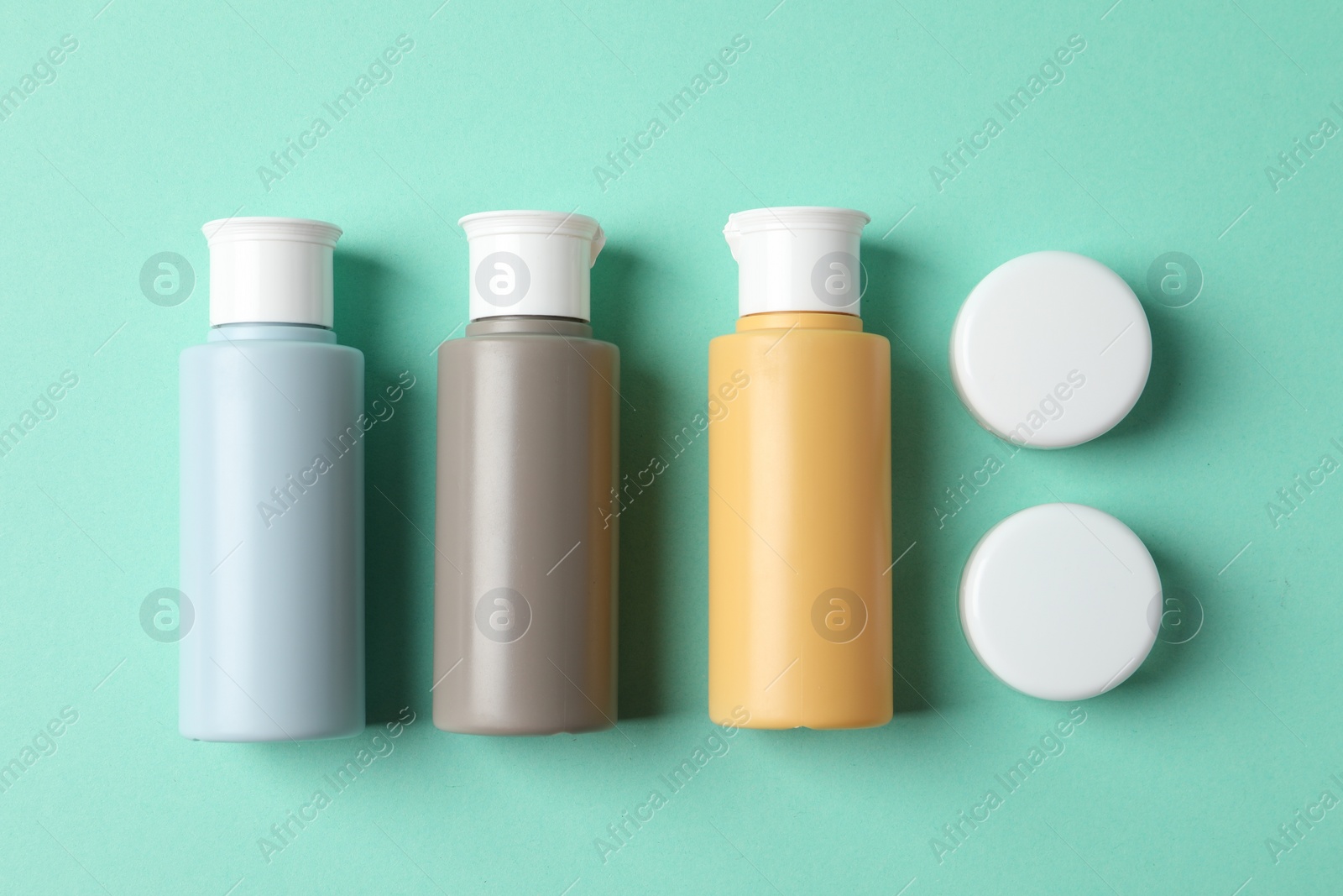 Photo of Cosmetic travel kit on turquoise background, flat lay. Bath accessories