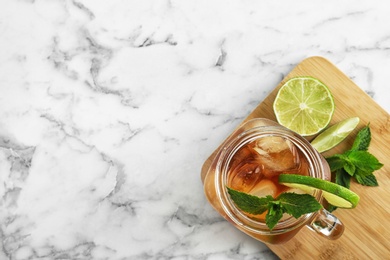 Mason jar of delicious iced tea on marble table, top view. Space for text