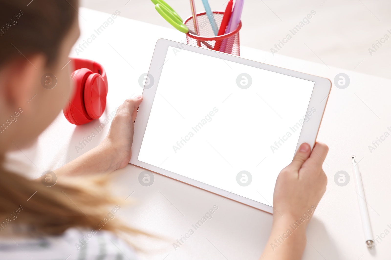 Photo of E-learning. Girl using tablet for studying online at table indoors, closeup