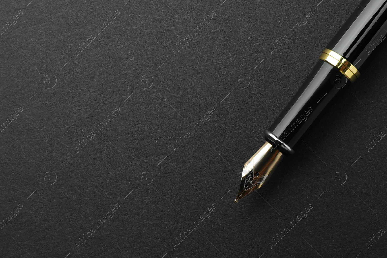 Photo of Stylish fountain pen on black background, top view. Space for text