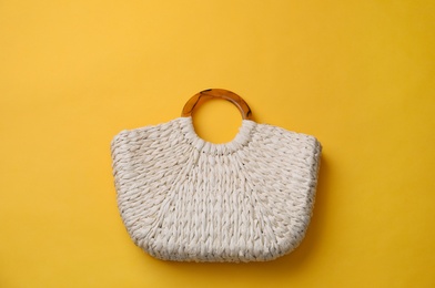 Photo of Stylish straw bag on yellow background, top view. Summer accessory
